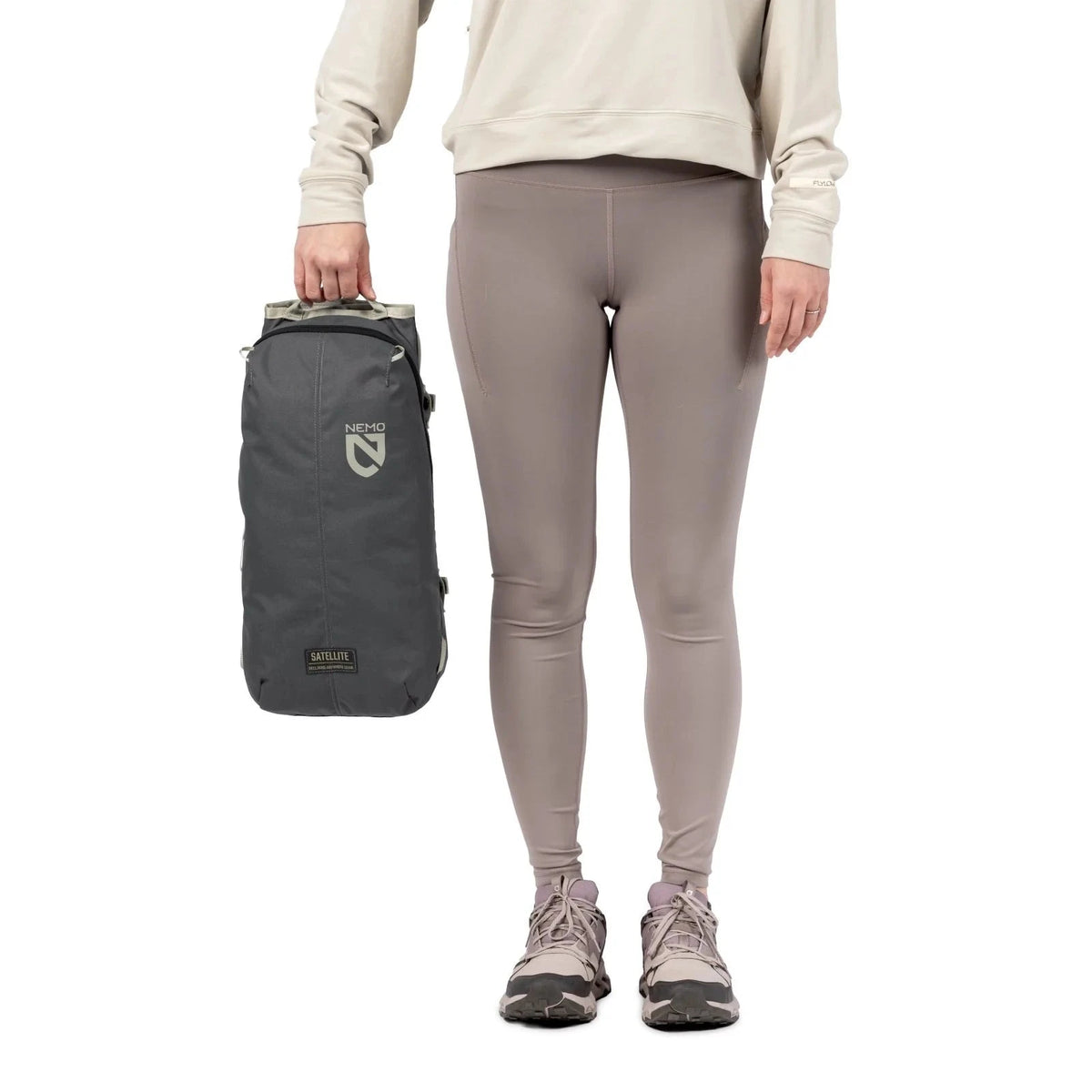 NEMO Satellite reclining chair carry bag in dark grey, held beside a person's leg